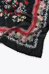 Pañuelo cuadrado de algodón color crema con estampado de flores rojas, rosadas, celestes y verdes. Tiene un borde con abalorios de colores.