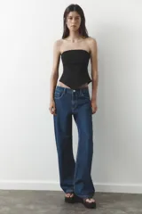 Pantalón de jean azul oscuro, de corte wide leg y tiro medio, con cinco bolsillos y cierre frontal con cremallera y botón metálico.
