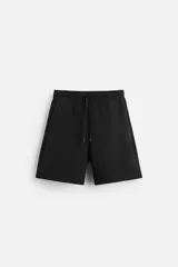 Bermuda negra relaxed fit confeccionada en tejido interlock de algodón con elasticidad. Cintura elástica ajustable con cordón. Bolsillos laterales y detalle de bolsillo trasero de plastrón.