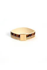 Brazalete ancho con estampado animal print y detalles de cadenas doradas y strass. Cierre magnético.