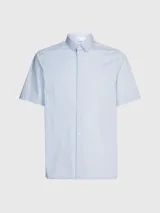 Camisa celeste de popelín de algodón superelástico, con cuello en punta, manga corta, tapeta con botones y logo con monograma de Calvin Klein en el pecho.