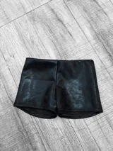 Short negro de cuero sintético, tiro bajo y corte ajustado.