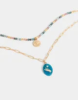 Collar corto dorado de doble cadena, una de eslabones y otra de cuentas de colores. Incluye un dije dorado con forma de sol y un dije azul con una figura grabada.