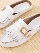 Mocasín mule blanco de cuero vacuno flor, con detalle de flecos en la capellada y hebilla metálica dorada.