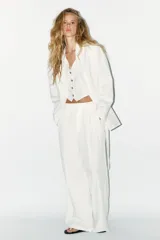 Blazer oversize color blanco confeccionado con 22% de lino. Tiene cuello solapa, manga larga con hombreras y abertura en la espalda. Incluye cinturón lazada en el mismo tejido.