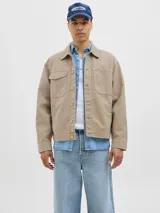 Campera de denim color beige, con cuello amplio, puños con botones y cierre frontal con botones. Incluye bolsillos en el pecho y laterales. Tejido denim de sarga resistente y con protección contra el viento.