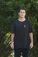 Remera negra de manga corta con cuello redondo y estampado pequeño en el pecho con un diseño abstracto en tonos naranja y amarillo.