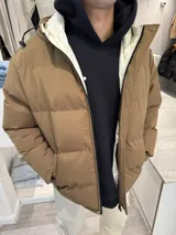 Campera puffer marrón claro con capucha y cierre frontal.