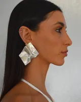 Aros colgantes plateados con forma geométrica irregular y diseño texturizado.