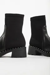 Botas negras de cuero con caña baja, taco cuadrado y detalle de tachas plateadas en la base.