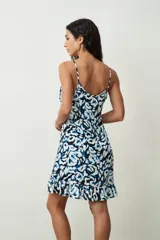 Vestido corto blanco de tirantes finos, con escote redondo y corte holgado tipo camisola, con un pequeño volante en el ruedo.