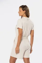 Mono corto color beige de lino, con cuello camisero, cierre frontal con botones, cinturón de lazo y bolsillos laterales.