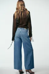 Pantalón de jean celeste de tiro alto, corte wide leg cropped, con cinco bolsillos y cinturón marrón con tachas.