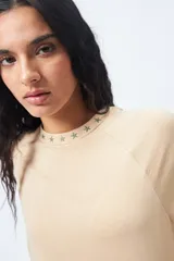 Remera negra de corte holgado con mangas ranglan y cuello redondo con bordado de estrellas blancas.