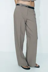 Pantalón de tiro alto con estampado a cuadros en tonos beige y marrón, con bolsillos delanteros y falsos bolsillos traseros. Incluye cinturón marrón con hebilla metálica.