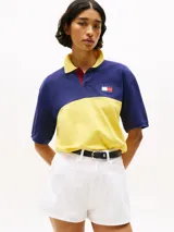 Chomba Tommy Hilfiger de corte amplio, con diseño color block en azul y amarillo, cuello clásico, cartera de tres botones, logo bordado en el pecho y logo oversize en la espalda.