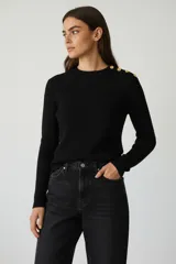 Sweater negro de tejido acanalado, manga larga y cuello redondo con detalle de botones dorados en el hombro.