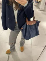 Bolso tote azul marino de nylon con detalles de cuero marrón en las asas y la solapa de cierre.