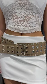 Cinturón marrón con hebilla metálica plateada y doble hilera de ojalillos metálicos.