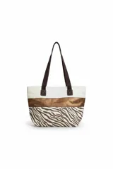 Bolso tipo tote bag de tela color beige con estampado de estrellas negras en la parte inferior y una franja horizontal negra brillante en el medio. Tiene asas de tela color beige claro y detalles de cuero sintético negro en los puntos de unión de las asas.