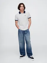 Remera polo de hombre Gap, a rayas horizontales blancas y azul marino. Cuello y mangas en azul marino. Logo de la marca bordado en el pecho.