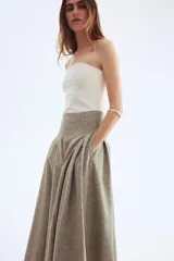 Pollera tobillera color beige con textura de lino, de tiro alto con cierre oculto y cierre de corchete atrás. Pinzas en la parte superior para crear una elegante y favorecedora silueta evasé. Forrada.