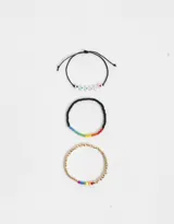 Set de tres pulseras elásticas: una con cuentas blancas con corazones de colores, otra con cuentas negras y detalle de arcoíris, y otra dorada con detalle de arcoíris.
