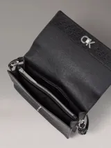 Cartera de hombro Calvin Klein color negro con monograma CK en toda la superficie y logo metálico plateado en el frente.