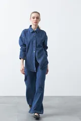 Jean wide leg de denim azul con tachas aplicadas en un patrón ondulado.