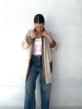 Camisa color beige con detalles en cuero color marrón en cuello, solapa, cierre y puños. Corte recto y abotonada al frente.