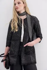 Saco negro de símil cuero con bordado de flores y calado en toda la prenda. Tiene cuello redondo, mangas largas y apertura frontal con broches ocultos.