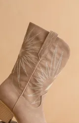 Bota texana corta color beige con bordado de rayos de sol en blanco.