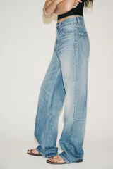 Pantalón de jean azul oscuro, de tiro alto, corte wide leg y largo hasta el tobillo.
