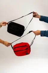 Bandolera roja con dos bolsillos frontales, correa ajustable y diseño funcional.