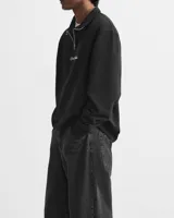 Buzo negro de cuello alto con cierre metálico y logo bordado en el pecho.