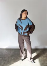 Sweater oversize tejido en punto jersey color celeste con mangas marrones y diseño de hoja abstracta en el frente.