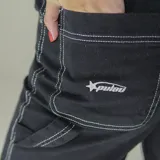 Pantalón negro de gabardina, corte recto y tiro alto, con costuras blancas a contraste.
