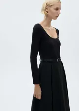 Vestido midi negro de punto con cuello redondo, mangas largas y falda acampanada. Incluye cinturón fino de cuero con hebilla metálica.