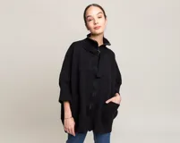 Tapado negro de tejido de punto grueso, con cuello alto, cierre frontal con cremallera y hebilla, mangas 3/4 y bolsillos laterales. Diseño holgado y cómodo.