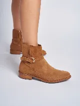 Bota corta de gamuza color marrón, con taco cuadrado y punta fina. Presenta una correa con hebilla dorada alrededor del tobillo y cierre lateral.