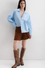 Camisa blanca de algodón con cuello clásico, mangas largas con puños abotonados y bolsillo de parche en el frente.