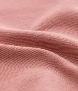 Pantalón clochard de jeans color rosa viejo, con cintura fruncida, cierre por botón y cremallera, pequeño bolsillo delantero y bolsillos delanteros y traseros.