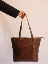 Bolso tote de cuero color marrón con cierre superior, bolsillo interior y porta llaves.