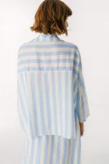 Camisa celeste y blanca a rayas verticales, de corte holgado y mangas largas.