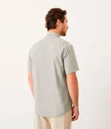 Camisa celeste de manga corta, corte comfort, con cuello abotonado y cierre frontal con botones.
