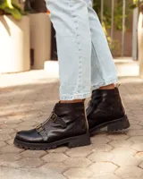 Botas de cuero negras con suela track, cierre frontal dorado y dos hebillas decorativas en el empeine.