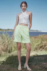 Bermuda de broderie color verde lima, de talle alto, con pliegues debajo de la cintura, piernas anchas con tablas y botamanga.