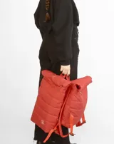 Mochila acolchada color ladrillo con cierre superior enrollable, correas ajustables y logo estampado en blanco.