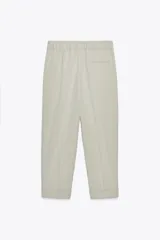 Pantalón color verde claro de tiro alto, con bolsillos delanteros, cintura elástica en la parte trasera y cierre frontal con cremallera y botones.