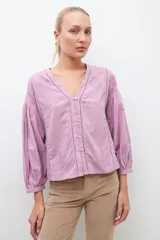 Blusa lila con bordados, de mangas largas abullonadas y cuello en V.